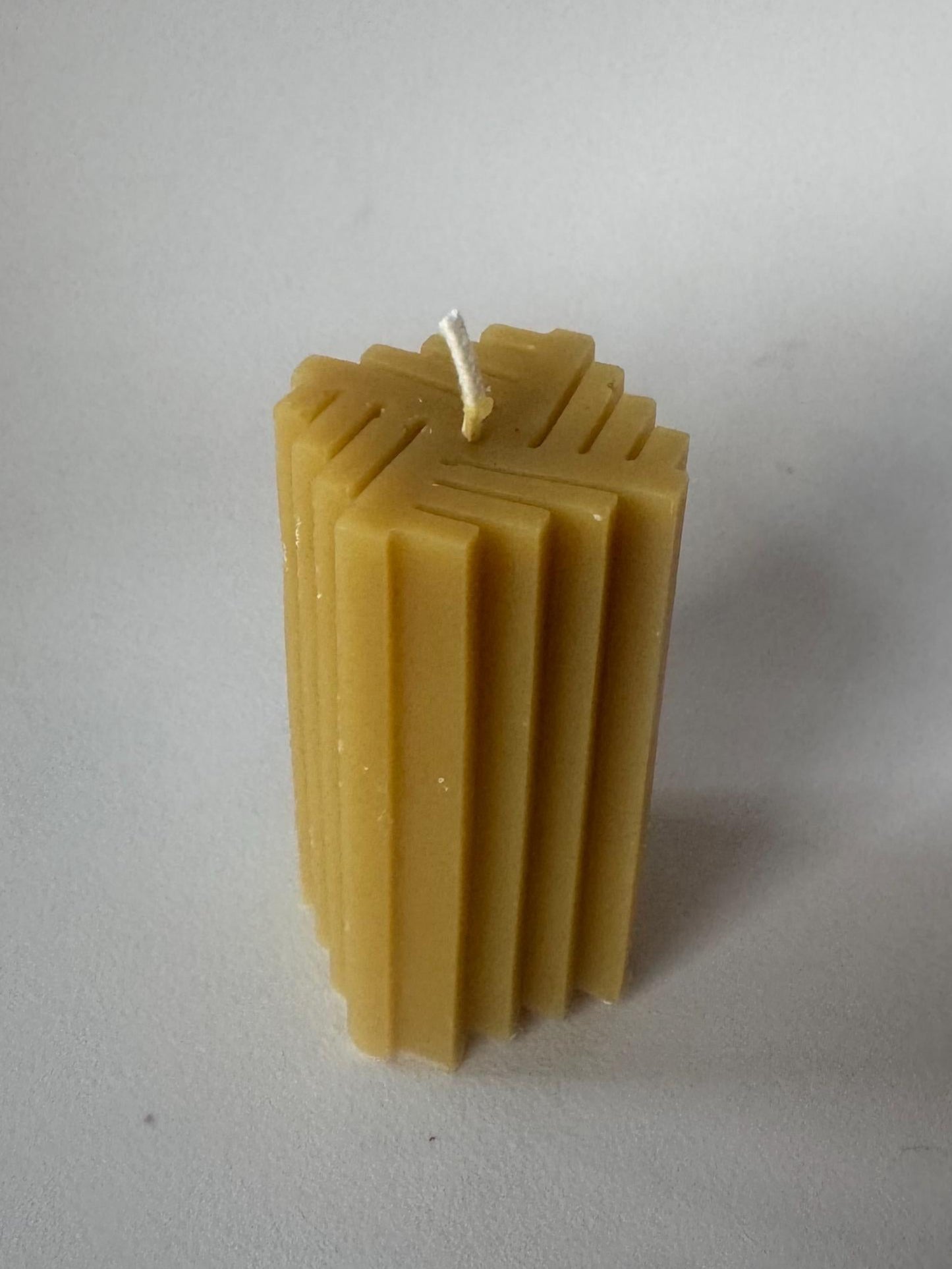 Beeswax candle with a textured surface on a plain background