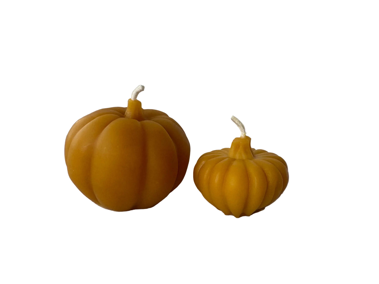 Two pumpkin-shaped beeswax candles on a white surface, one larger than the other