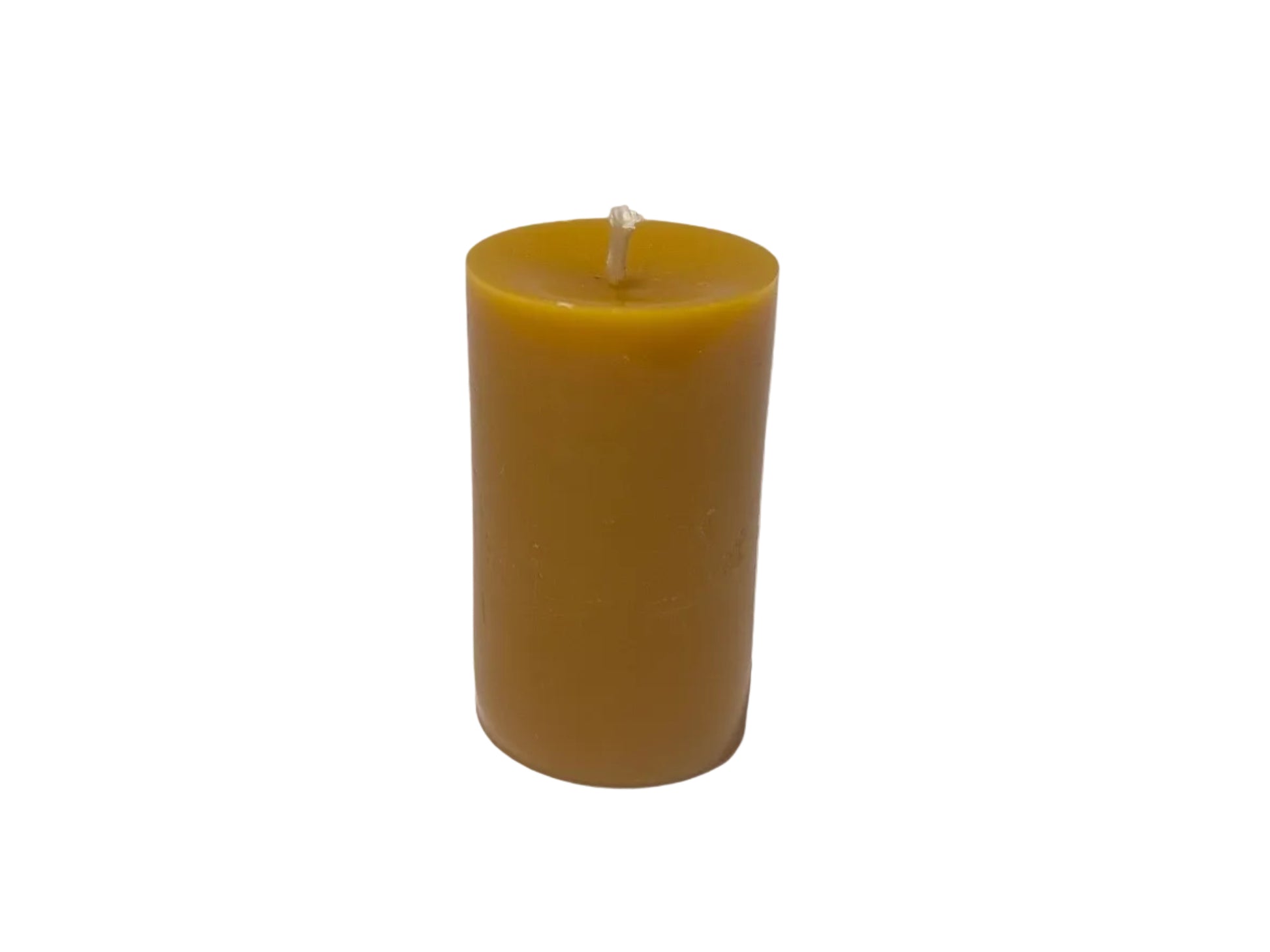 Yellow beeswax pillar candle on a white surface with a blurred background