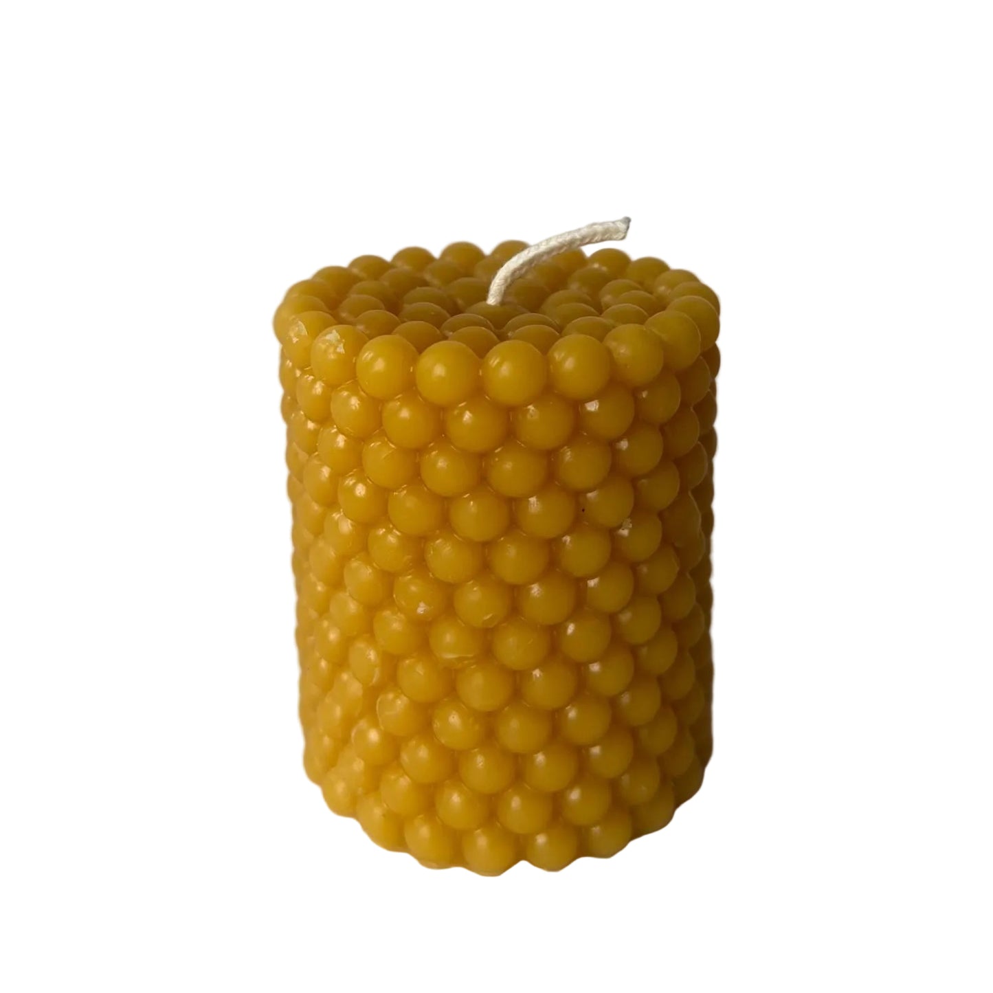 Yellow bubble-patterned candle  made of beeswax on a white background