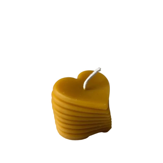 Yellow heart-shaped candle made of beeswax on a white background