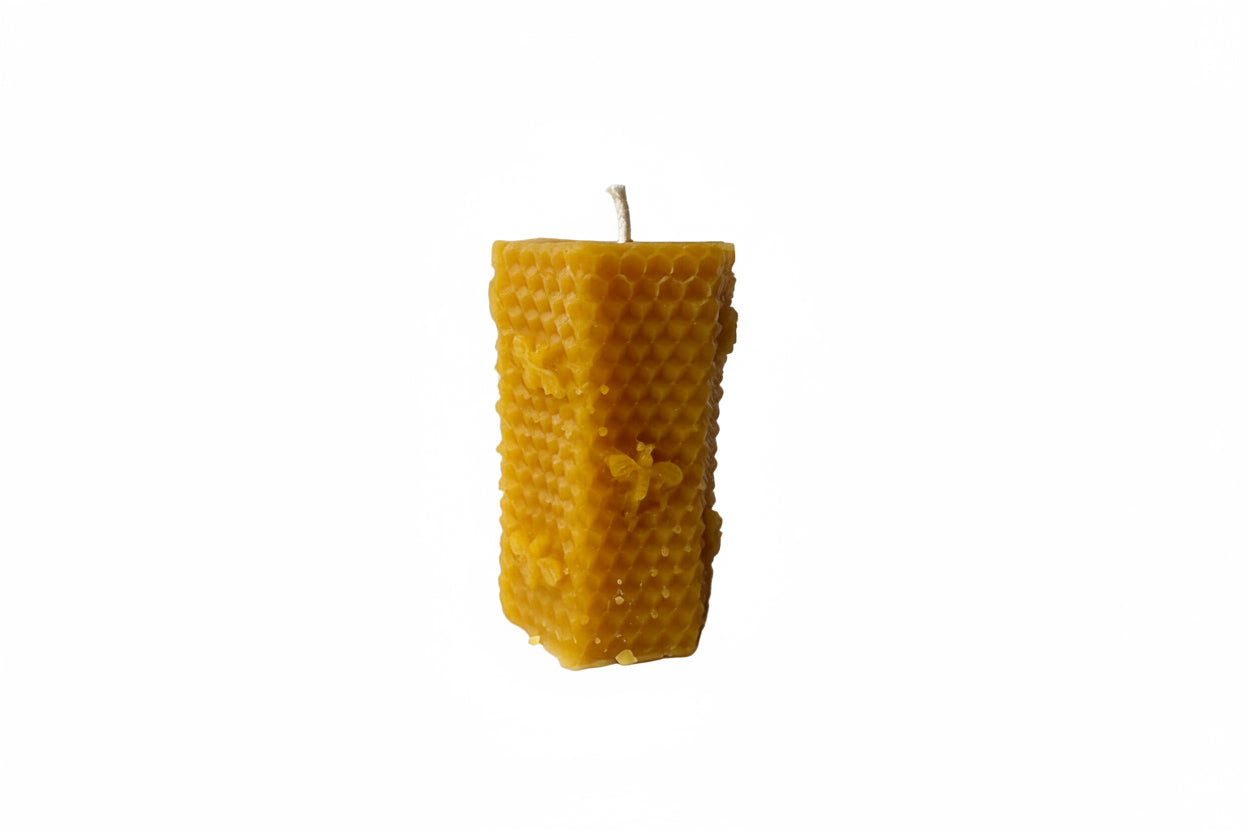 Hexagonal honeycomb candle made of beeswax on a gray background