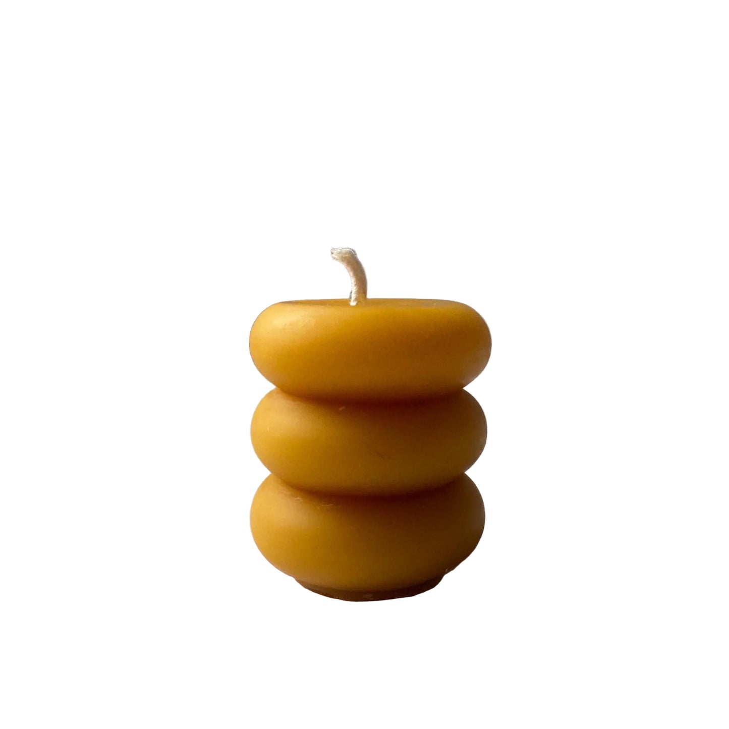 pillar candle made of beeswax  with 3 round layers on a light gray background