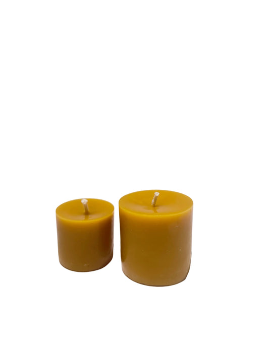 Two yellow beeswax pillar  candles on a white background