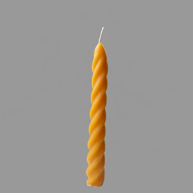 Yellow twisted candle on a gray background