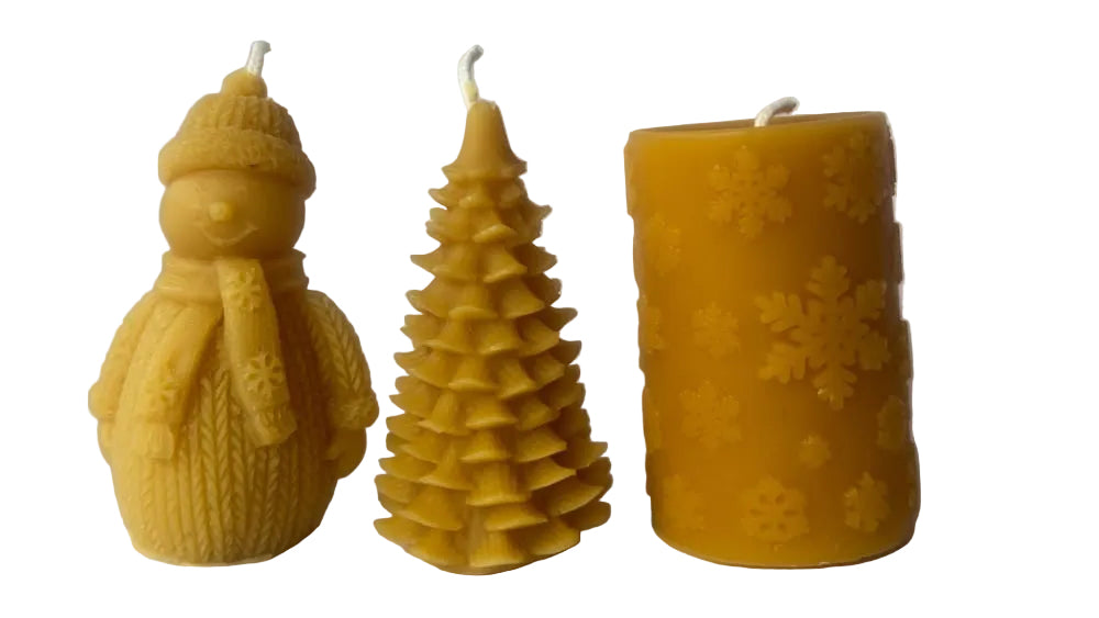 Snowman, Evergreen Tree, and Snowflake pillar candles made of beeswax on a white background